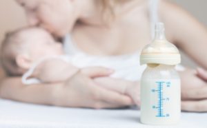 Breast-Pump-Bottle-In-Front-Of-Mother-With-Child