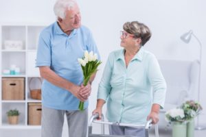 Man-Giving-Woman-With-Walker-Flowers