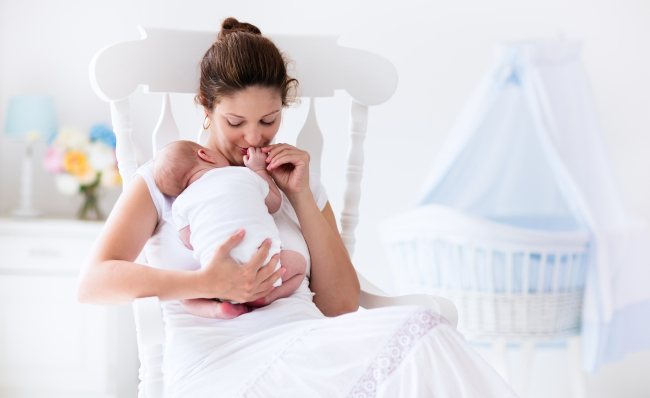 New-Mom-Holding-Baby-In-Nursery