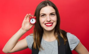 Woman-Holding-Clock-Up-To-Ear